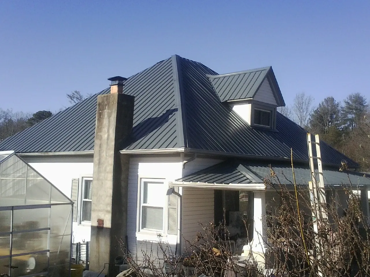 Dark blue standing seam metal roof on a white farmhouse with dormer — Slate & Tile Roof Repair by Roofing Brothers in Depew