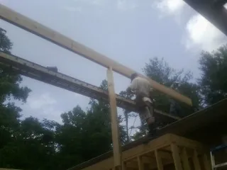 Carpenter setting a ridge beam over a new addition frame — Ice Dam Removal by Roofing Brothers in Depew