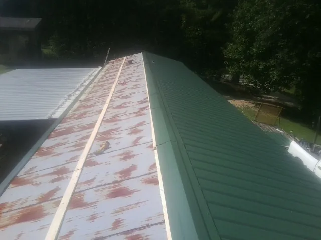 Old rusted panels beside newly installed green metal roofing — Wind Damage Roof Repair by Roofing Brothers in Depew