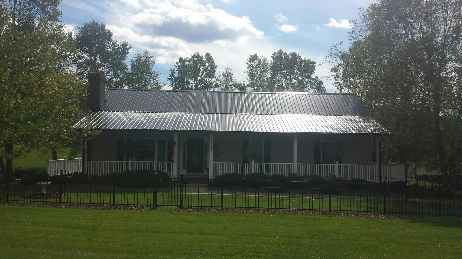 Gray metal roof on a brick ranch with a full width front porch — Gutter Guard Installation work by our crew in Depew