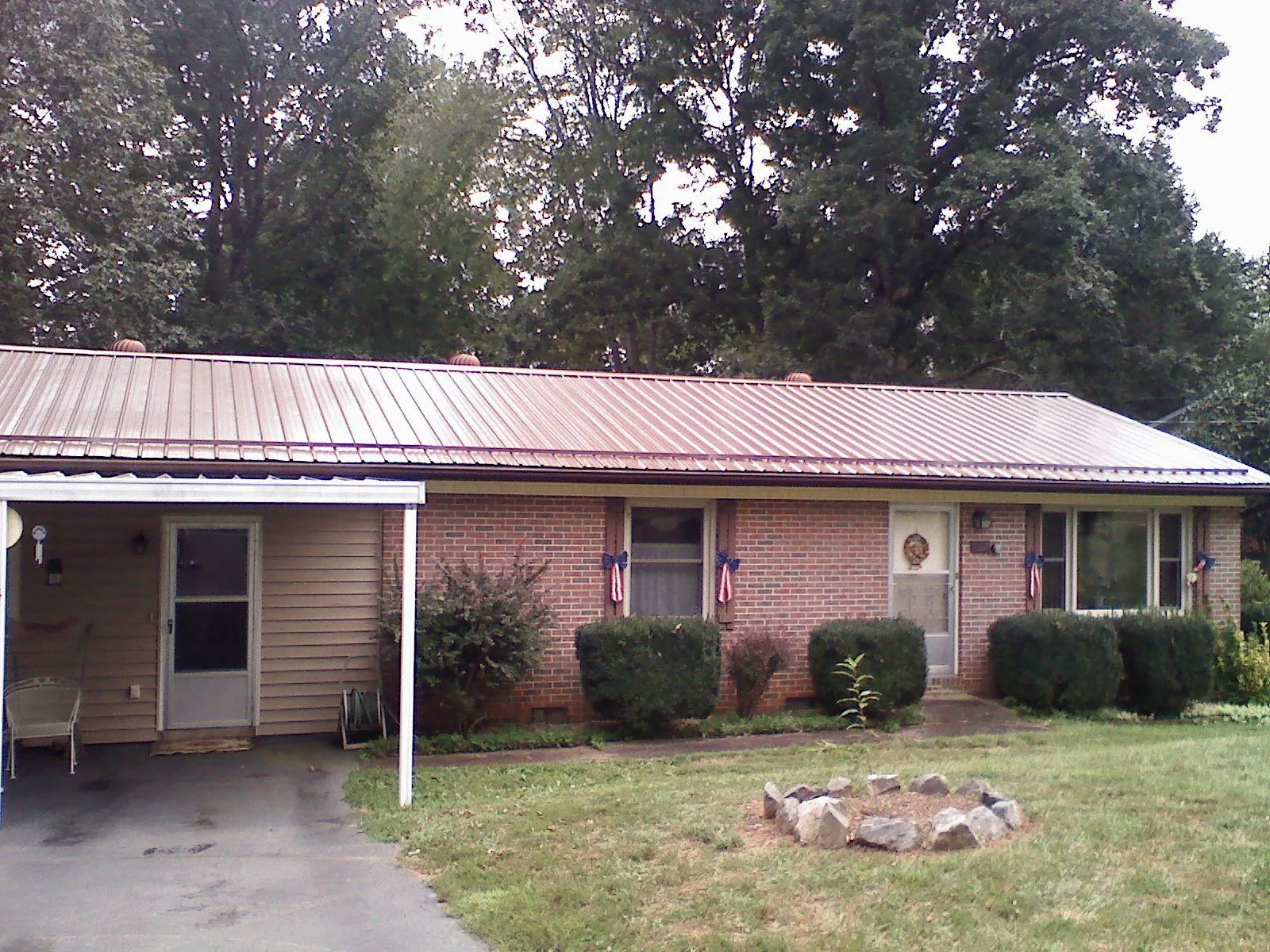 Bronze metal roof and carport on a brick ranch home — Roof Repair work by our crew in Depew