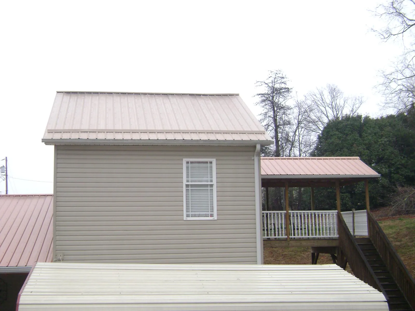 Tan metal roofs on a two story addition and attached porch, from a Roof Replacement job in Depew